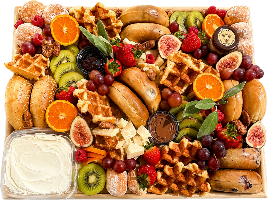 Assorted breakfast items including waffles, fruits, and pastries on a white background